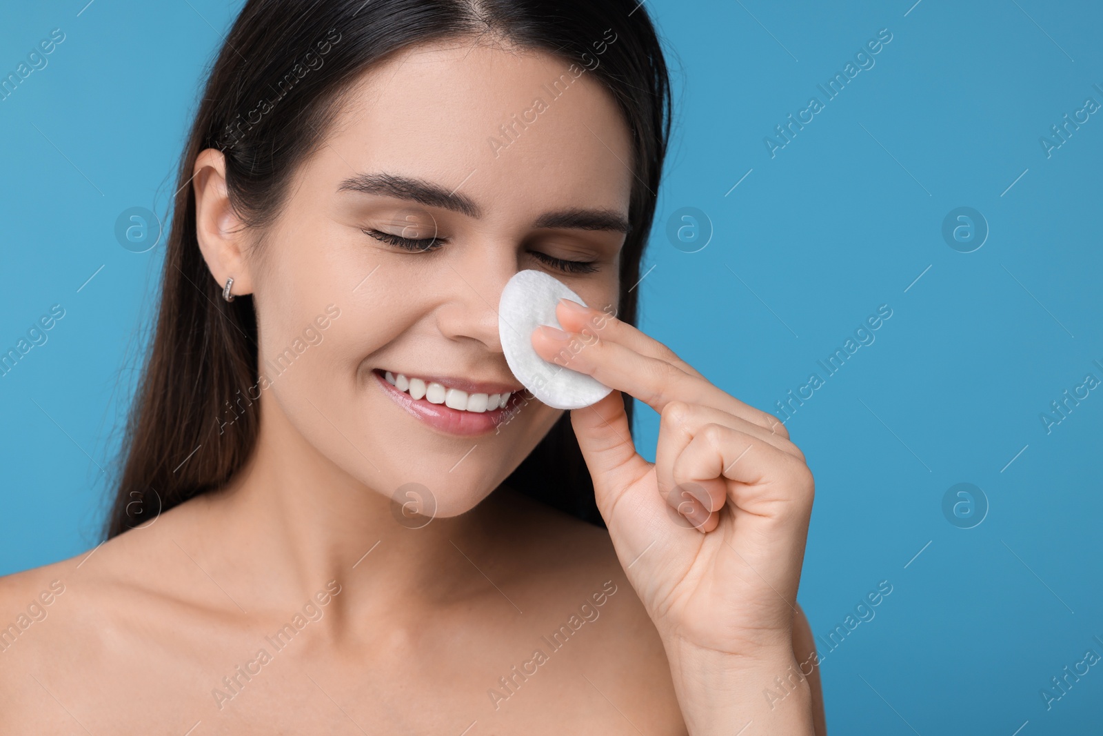 Photo of Young woman with cotton pad on light blue background