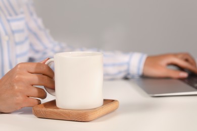 Photo of Woman with white ceramic mug at workplace, closeup