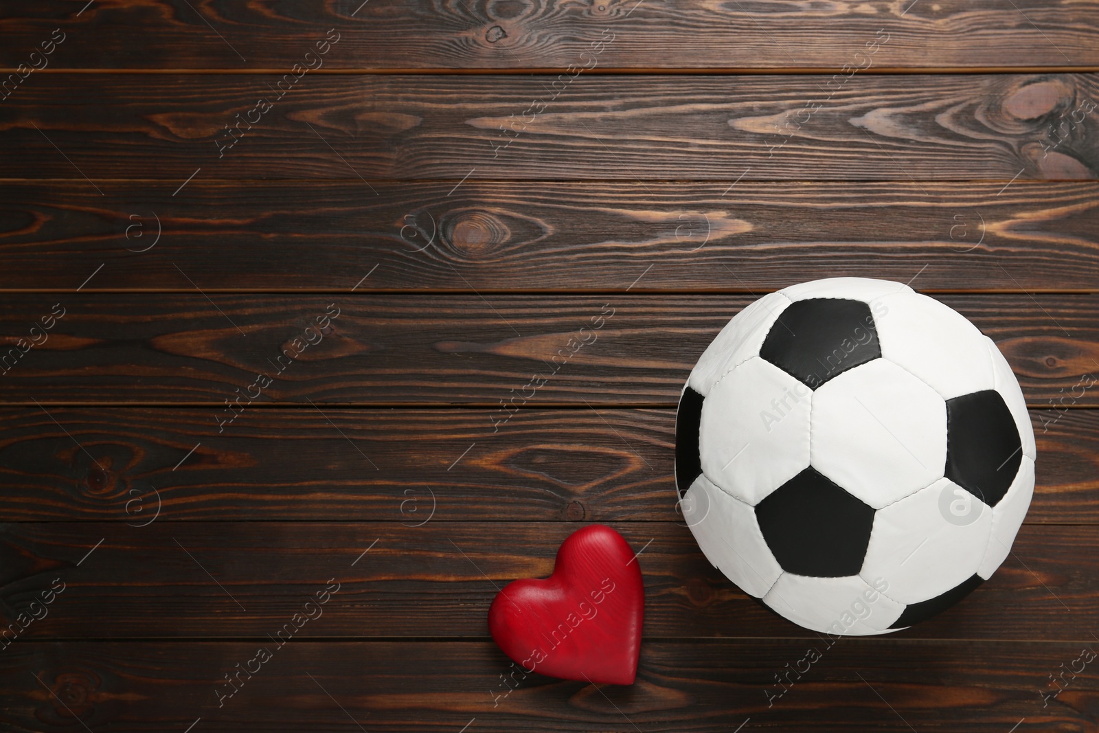 Photo of Soccer ball and heart on wooden background, flat lay. Space for text