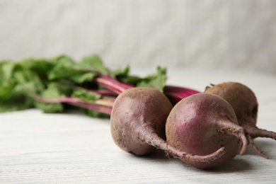 Bunch of fresh beets with leaves on wooden table against white background, closeup. Space for text