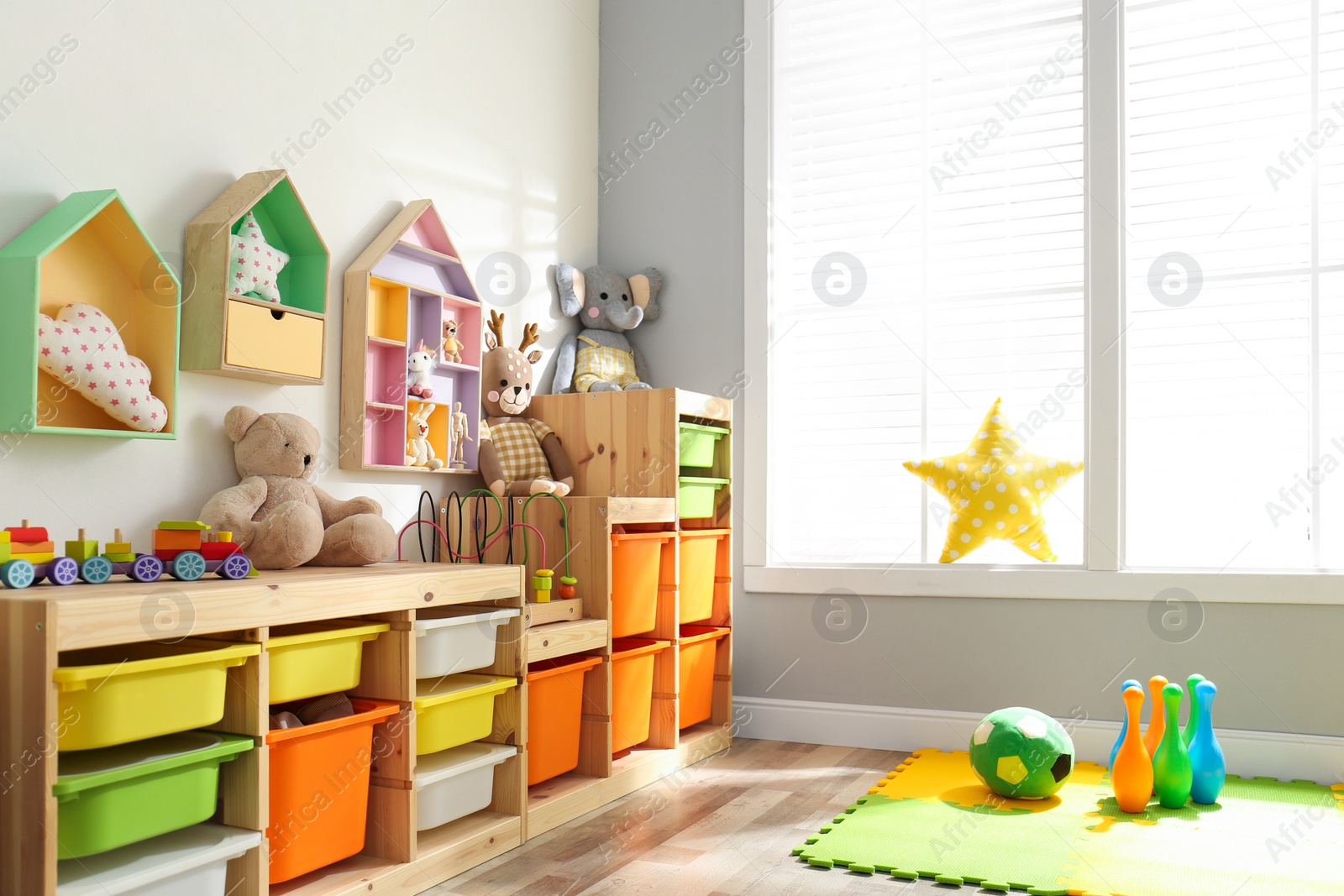 Photo of Stylish playroom interior with shelving unit and different soft toys