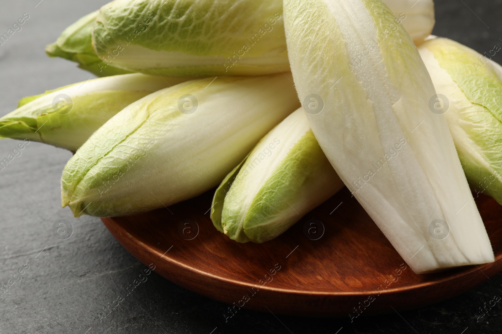 Photo of Fresh raw Belgian endives (chicory) on black table, closeup