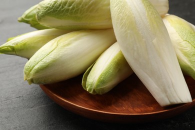 Fresh raw Belgian endives (chicory) on black table, closeup