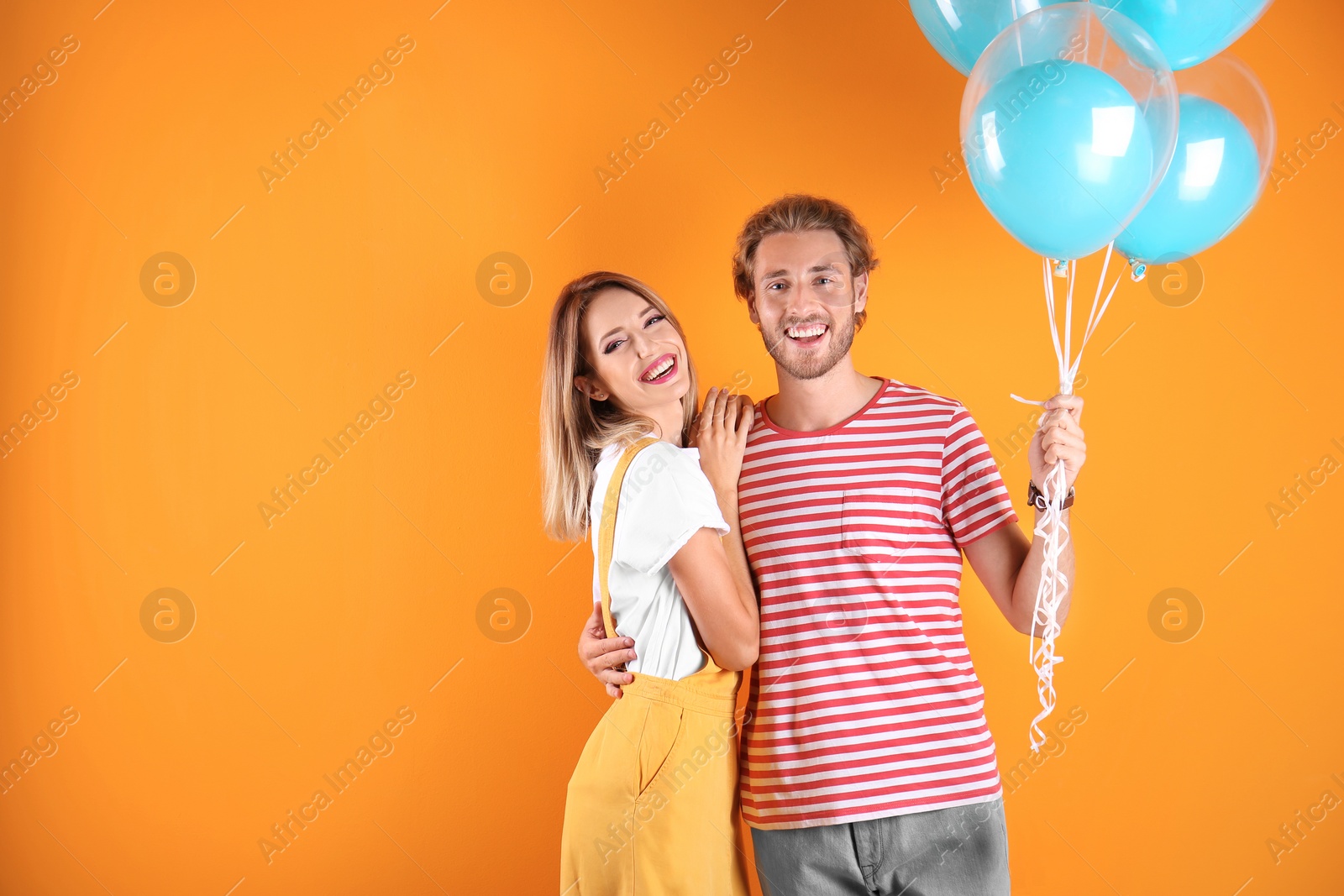 Photo of Young couple with air balloons and space for text on color background