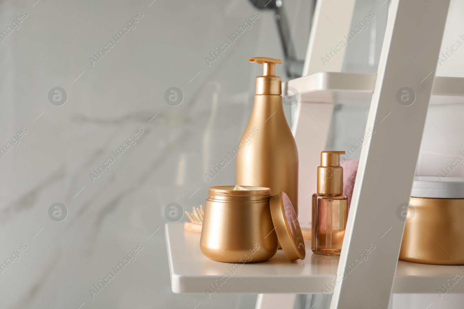 Photo of Different hair care products and towel on shelving unit in bathroom. Space for text