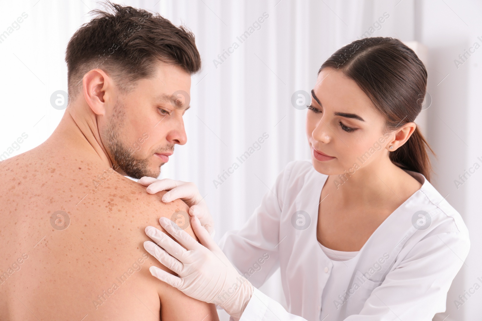 Photo of Doctor examining patient in clinic. Visiting dermatologist