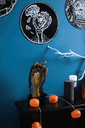 Jack-o'-lanterns and different Halloween decorations on black fireplace near blue wall