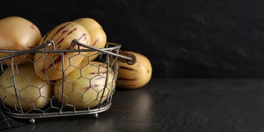 Fresh ripe pepino melons in metal basket on black table, space for text. Banner design