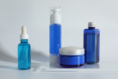 Photo of Different containers with cosmetic products on light background