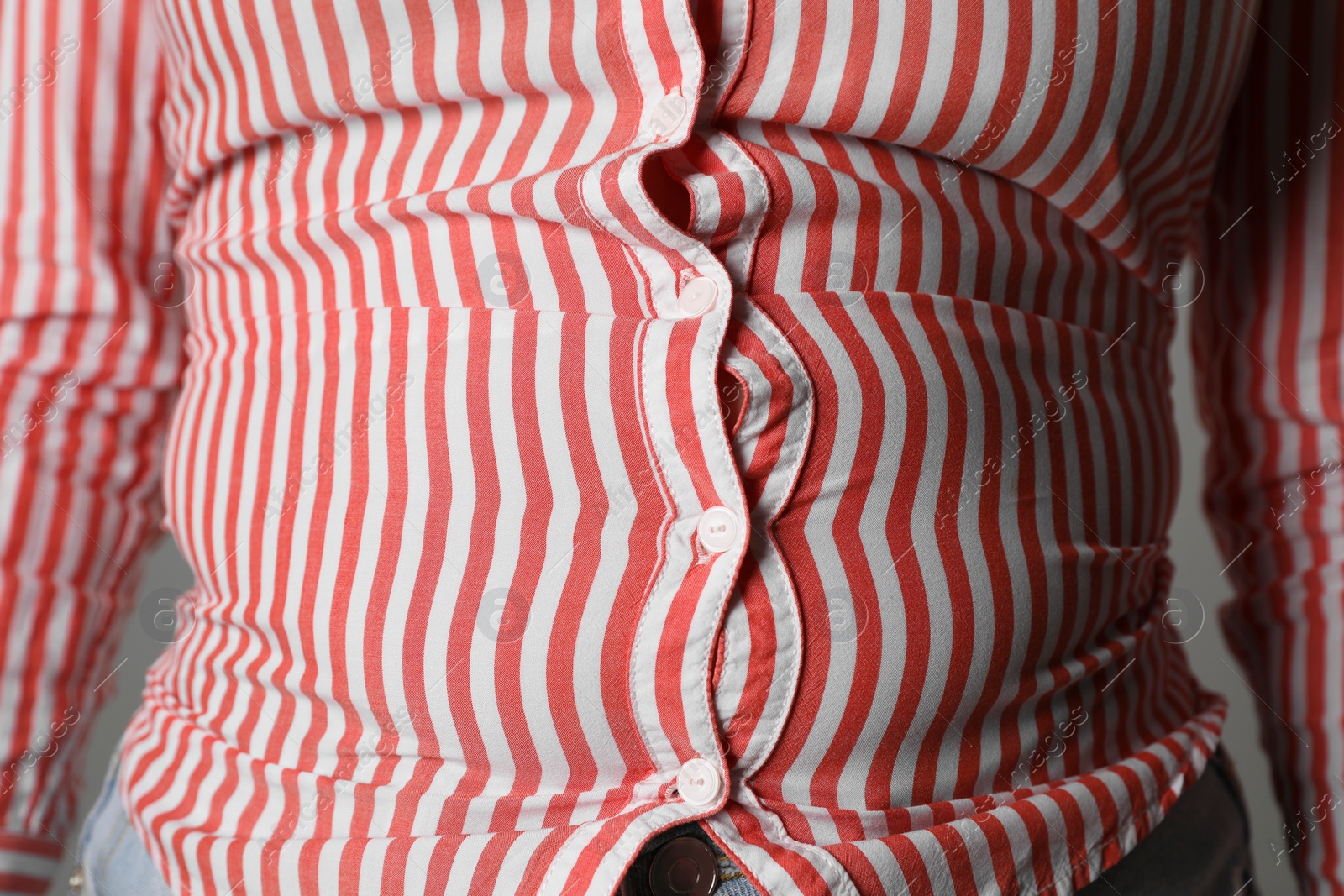 Photo of Overweight woman in tight shirt on grey background, closeup