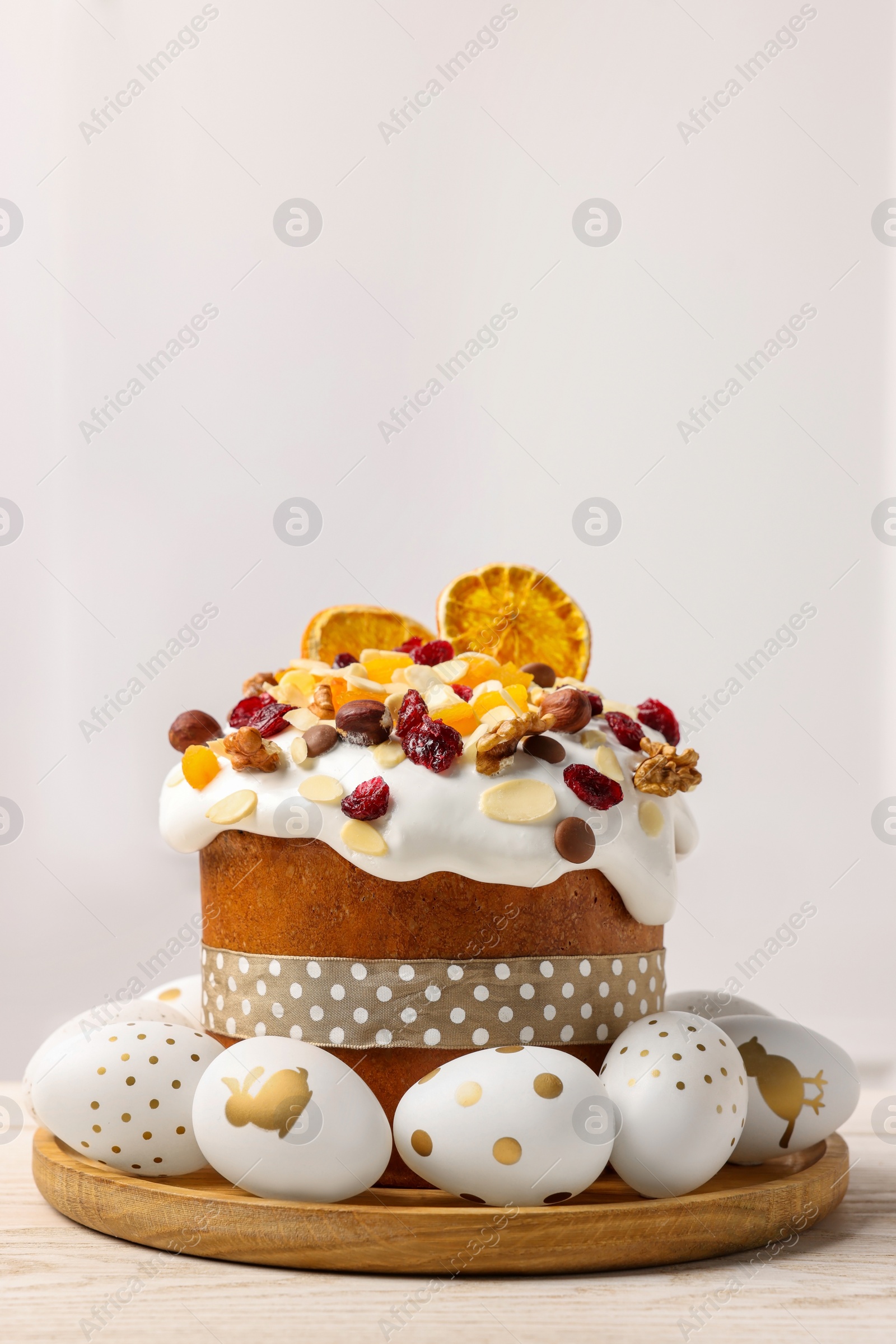 Photo of Traditional Easter cake with dried fruits and decorated eggs on white wooden table indoors