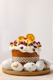 Traditional Easter cake with dried fruits and decorated eggs on white wooden table indoors