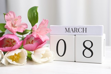 Photo of International Women's day - 8th of March. Wooden block calendar and beautiful flowers on white table