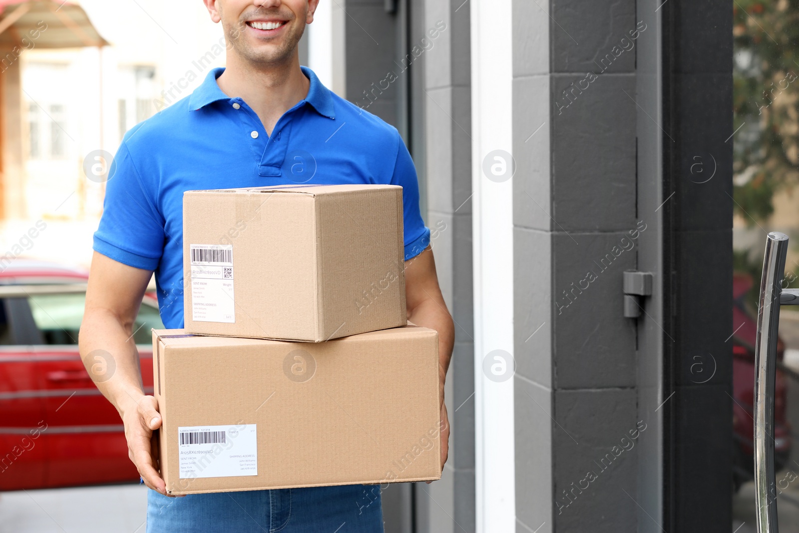 Photo of Delivery service courier with parcels in hands outdoors