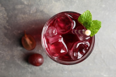 Photo of Delicious grape soda water on grey table, flat lay. Refreshing drink