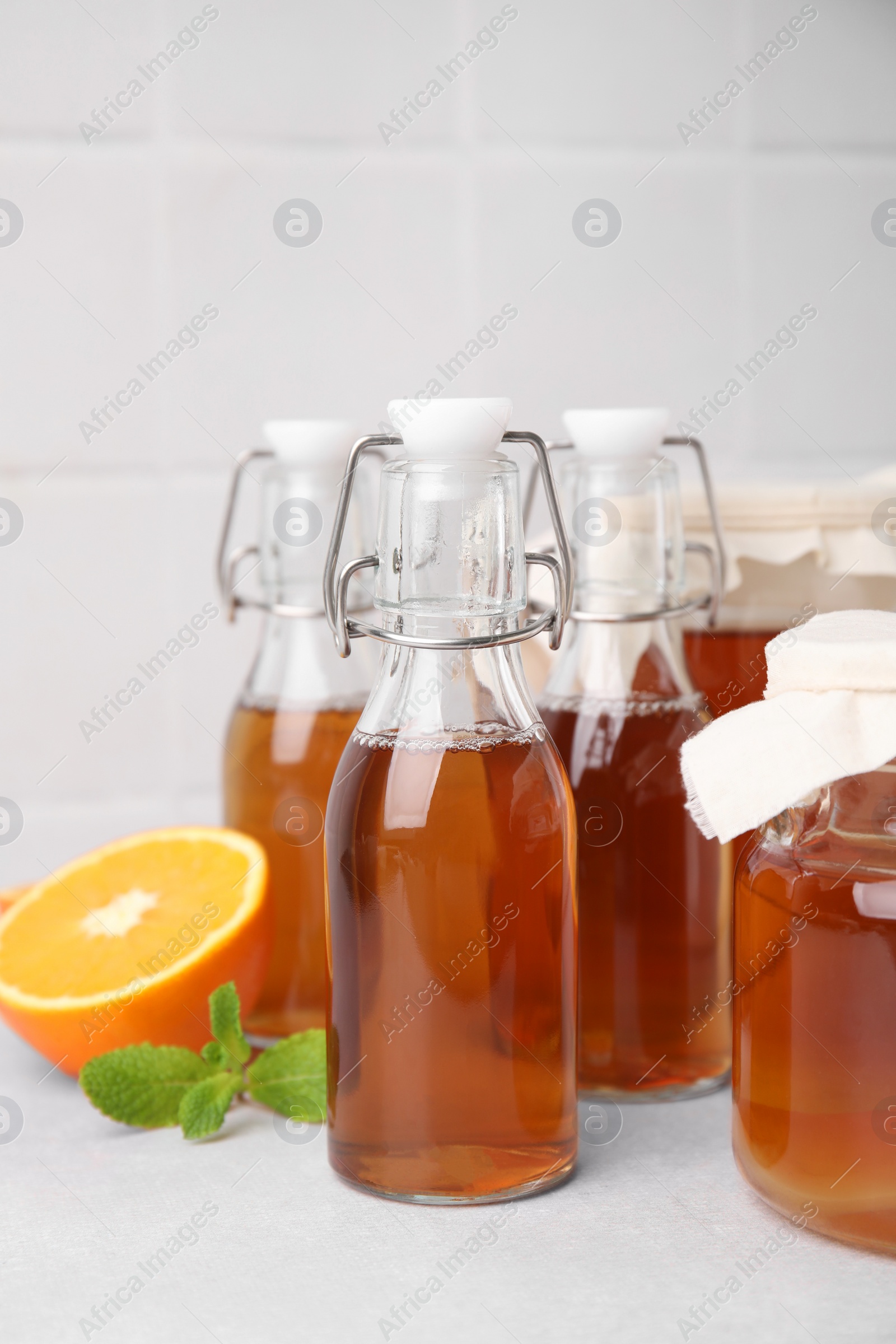 Photo of Tasty kombucha, orange and mint on white table