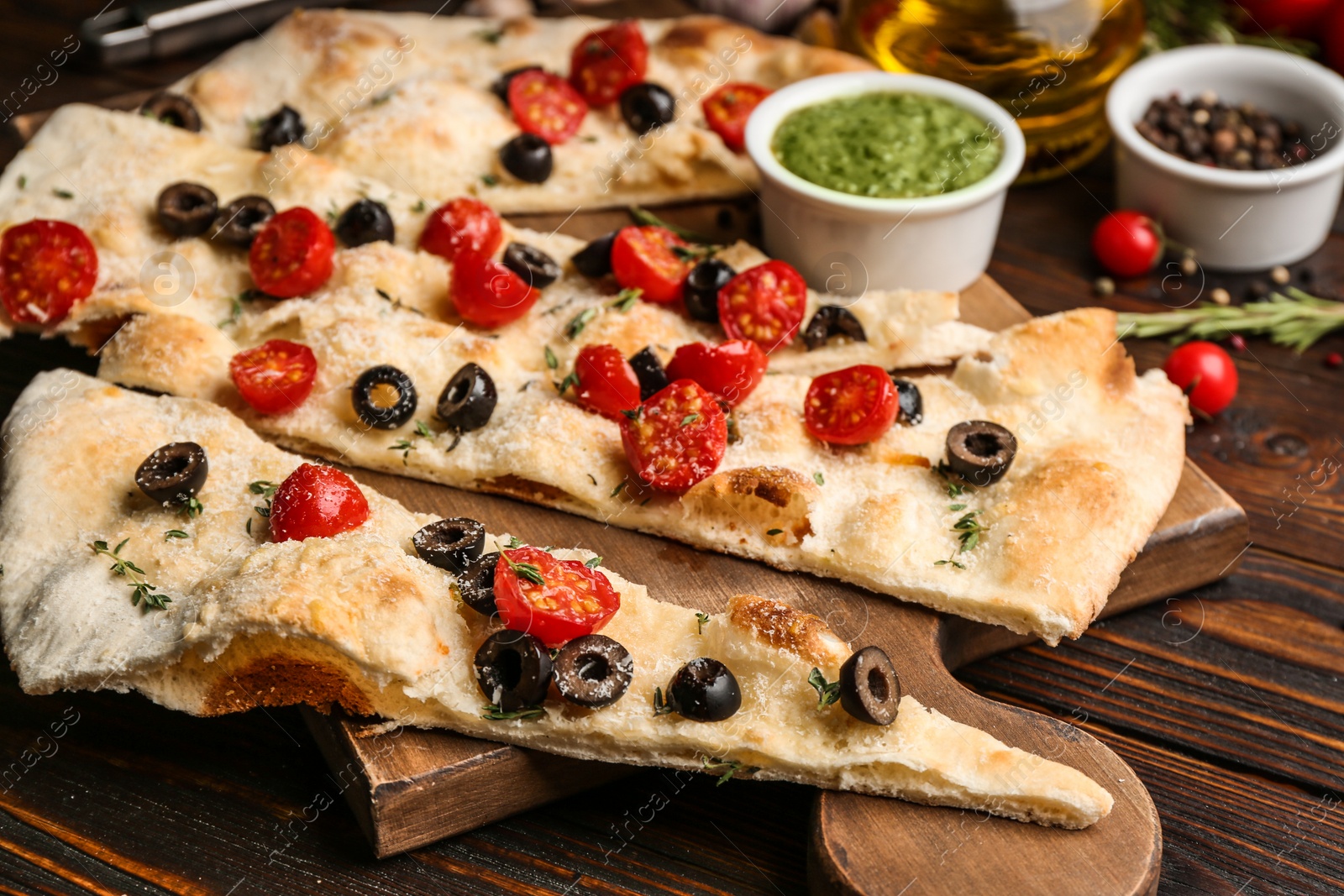 Photo of Focaccia bread with olives and tomatoes on wooden table, closeup