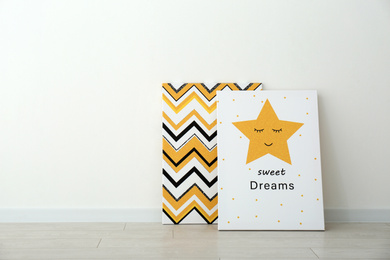 Photo of Adorable pictures of zigzag pattern and star with words SWEET DREAMS on floor near white wall, space for text. Children's room interior elements
