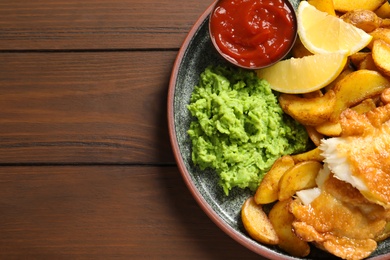 Photo of Plate with British traditional fish and potato chips on wooden background, top view. Space for text