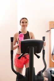 Athletic young woman with protein shake on running machine in gym
