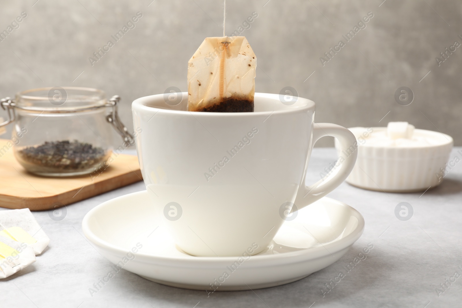 Photo of Tea brewing. Putting tea bag into cup on light table, closeup