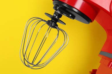 Photo of Closeup view of modern red stand mixer on yellow background