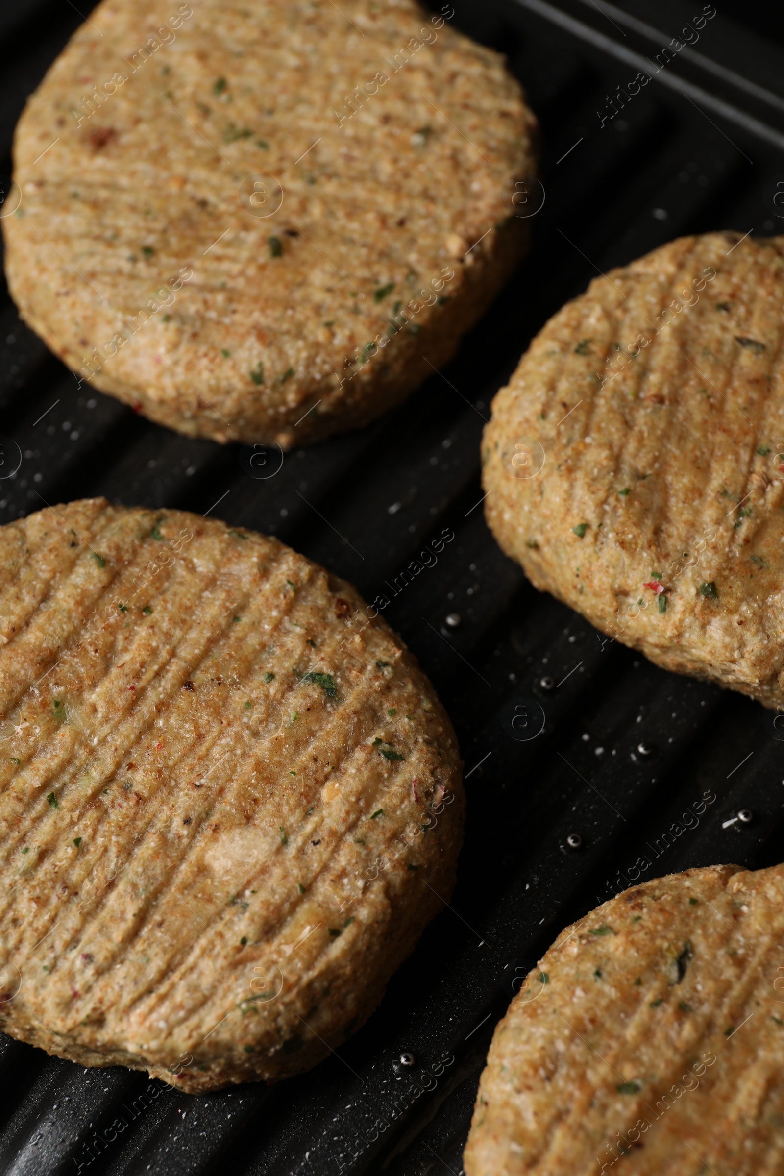 Photo of Delicious vegan cutlets cooking on electric grill, closeup