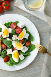 Photo of Delicious salad with boiled eggs, feta cheese and tomatoes served on wooden table, flat lay