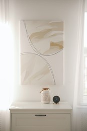 Modern white chest of drawers and painting in room. Interior design