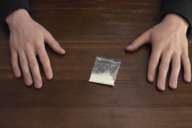 Criminal with drug at wooden table, above view