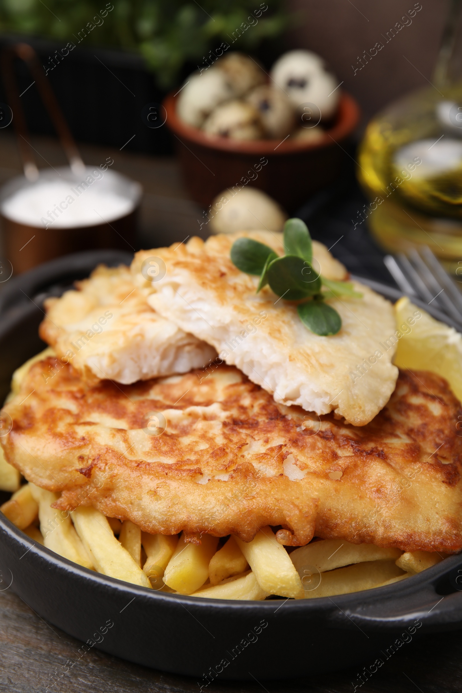 Photo of Tasty soda water battered fish and potato chips on wooden table, closeup