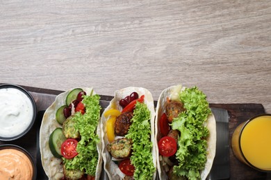 Photo of Delicious fresh vegan tacos served on wooden table, top view. Space for text