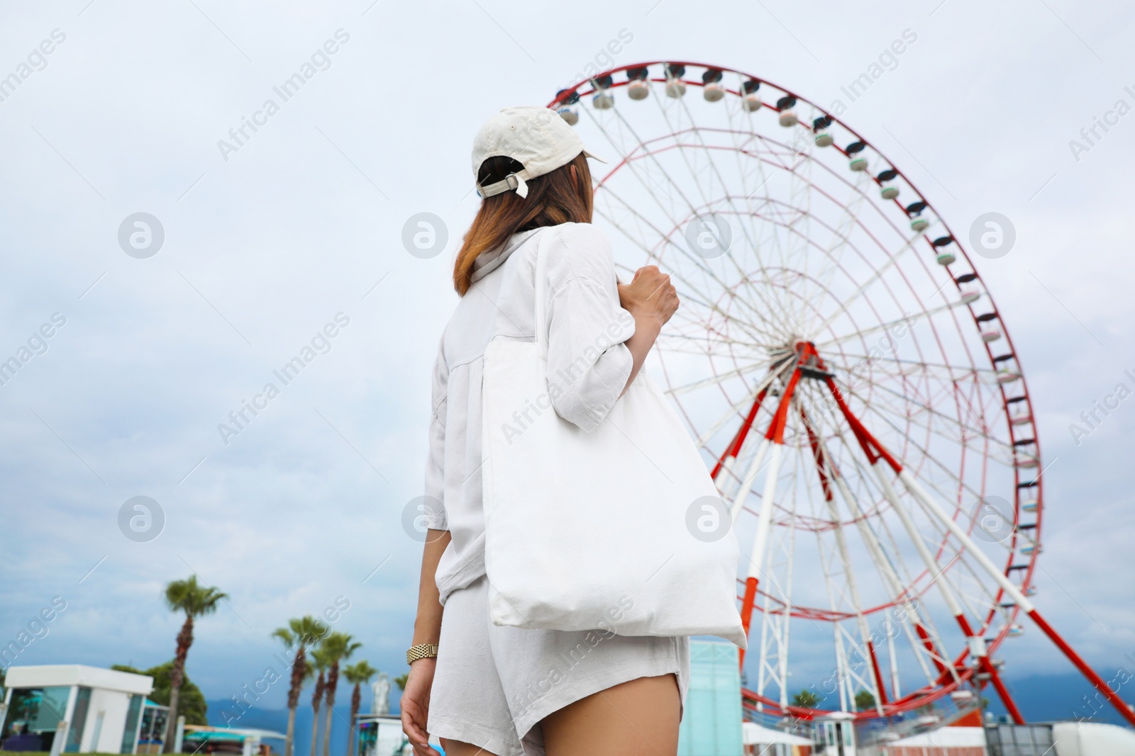 Photo of Young woman near Ferris wheel outdoors, back view