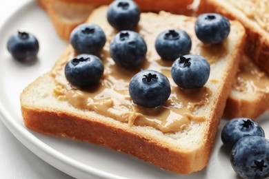 Photo of Delicious toasts with peanut butter and blueberries on table, closeup