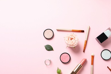 Flat lay composition with products for decorative makeup on pastel pink background