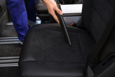 Car wash worker vacuuming automobile seat, closeup