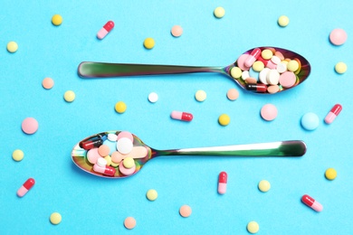 Spoons and different pills on color background