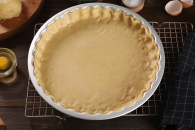 Photo of Pie tin with fresh dough and ingredients on wooden table. Making quiche