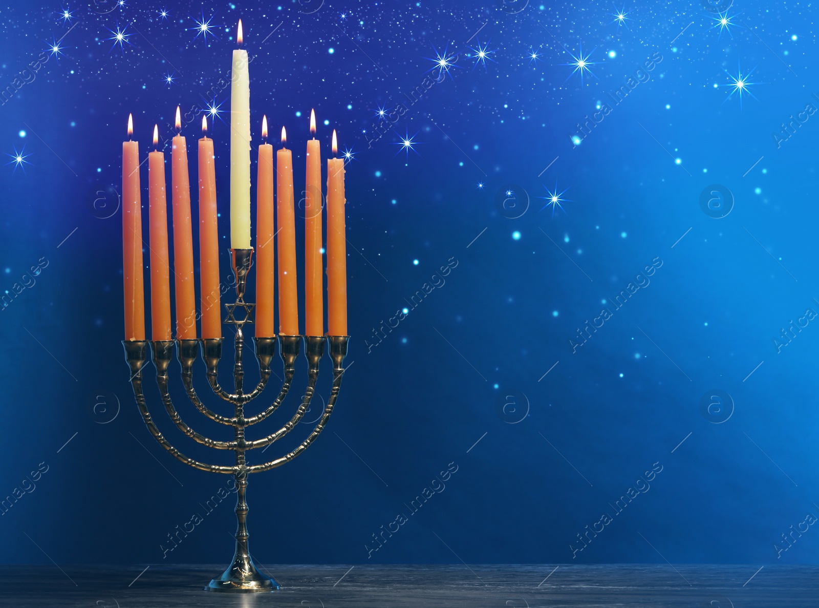 Image of Hanukkah celebration. Menorah with burning candles on wooden table against blue background, space for text