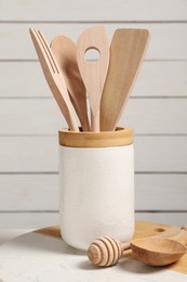 Photo of Holder with set of different kitchen utensils on white table