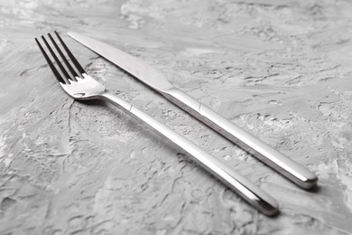 Stylish cutlery. Silver knife and fork on grey textured table, closeup