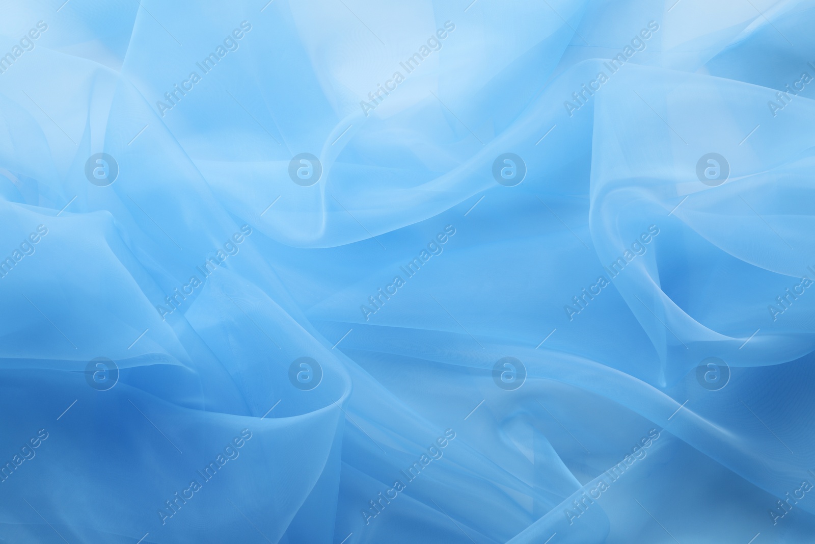 Photo of Beautiful light blue tulle fabric as background, closeup