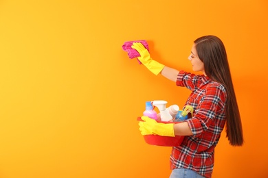 Photo of Young woman cleaning color wall with rag