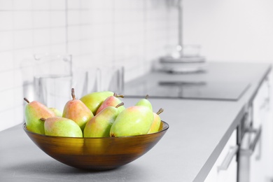 Photo of Fresh ripe pears on grey countertop in kitchen. Space for text