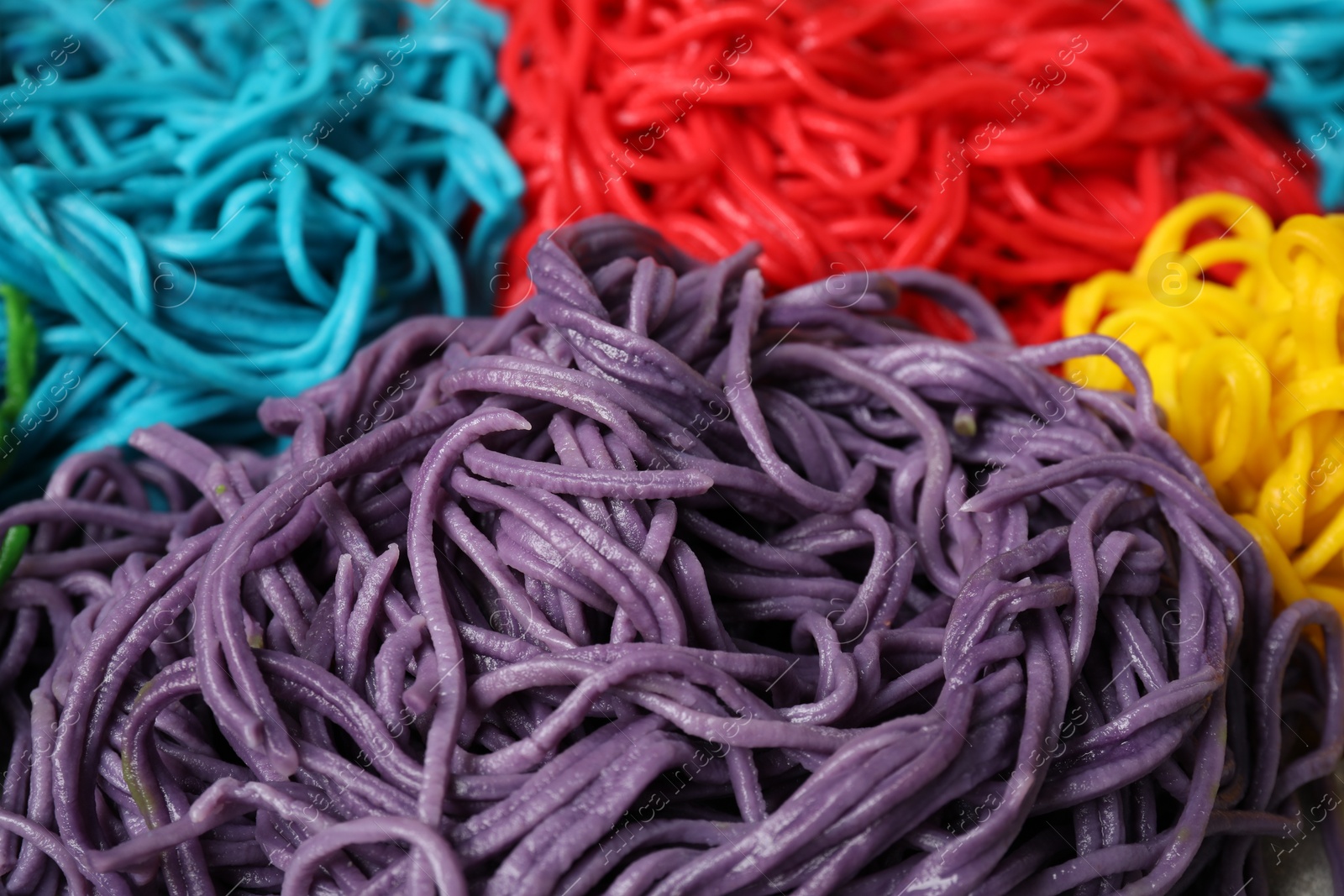 Photo of Rolled spaghetti painted with different food colorings as background, closeup