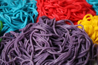Photo of Rolled spaghetti painted with different food colorings as background, closeup