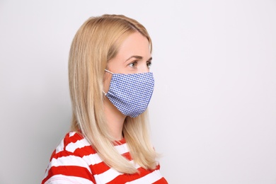 Photo of Woman wearing handmade cloth mask on white background, space for text. Personal protective equipment during COVID-19 pandemic