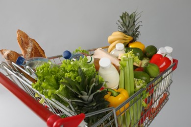 Photo of Shopping cart full of groceries on grey background