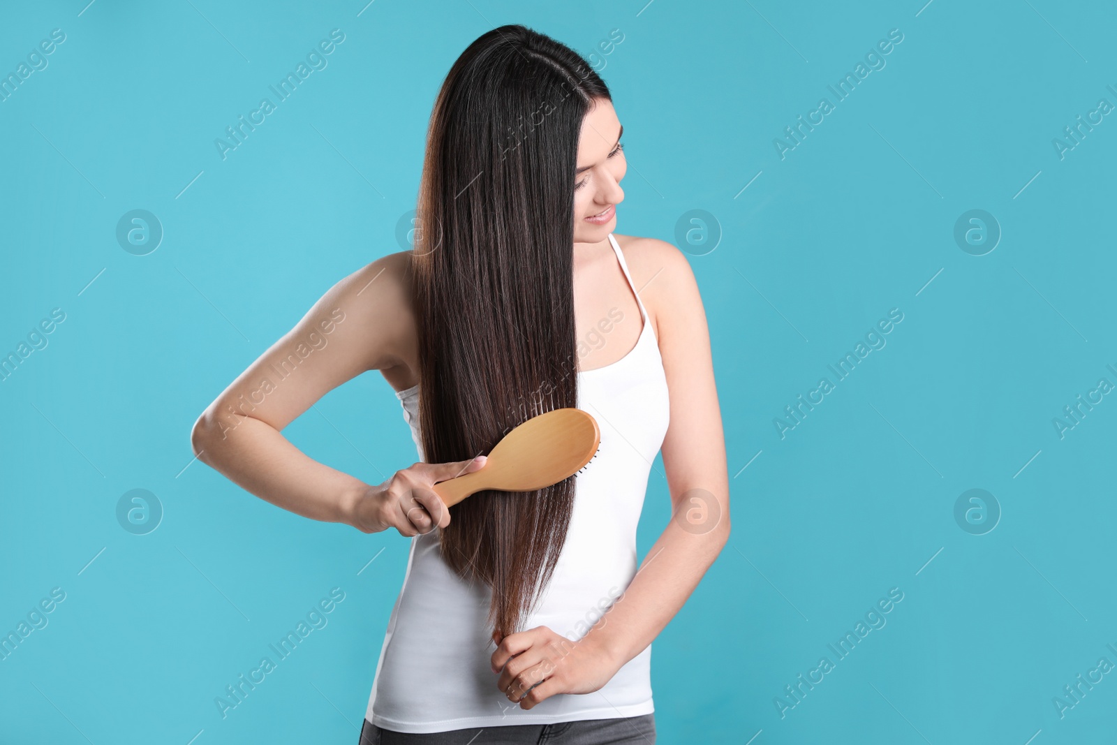 Photo of Beautiful young woman with hair brush on color background