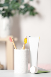 Photo of Bamboo toothbrushes and paste on light table indoors